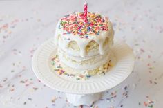 a birthday cake with white frosting and sprinkles on a small plate