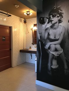 a black and white photo of a woman sitting on a toilet next to a bathroom sink