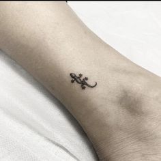 a small lizard tattoo on the left arm and foot, it looks like an animal