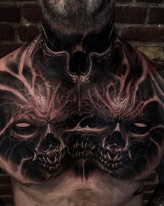 a man's chest covered in tattoos and demon masks, with his eyes closed