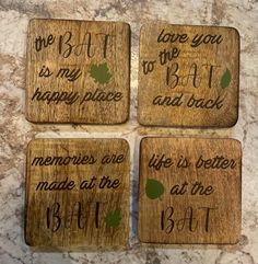 four wooden coasters with handwritten words on them sitting on a marble counter top