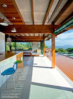 an outdoor kitchen and dining area on the deck overlooking the ocean, with blue chairs