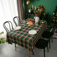 the table is set for christmas dinner with green walls and plaid tablecloths on it