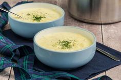 two blue bowls filled with soup on top of a table