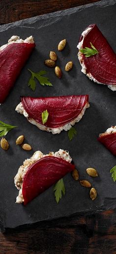 some food is laying out on a slate board with nuts and garnishes