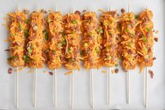 several skewered food items sitting on top of a white tray with toothpicks