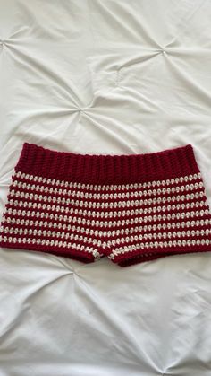 a red and white knitted shorts laying on top of a bed