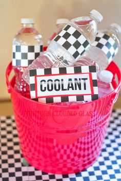 a red bucket filled with bottles of water on top of a checkered table cloth