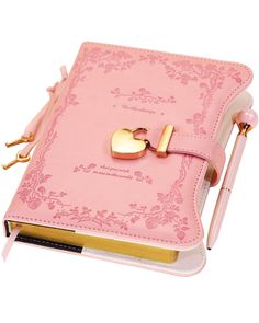 a pink notebook with a gold letter on it and a key attached to the cover