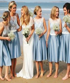 a group of women standing next to each other on top of a sandy beach near the ocean