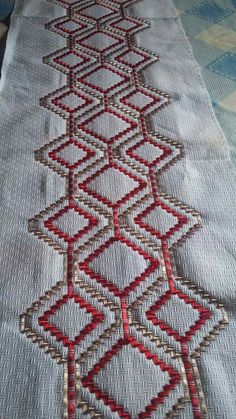 an embroidered table runner with red and white designs