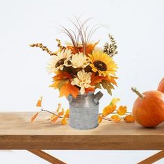 an arrangement of sunflowers, pumpkins and other autumn flowers on a table