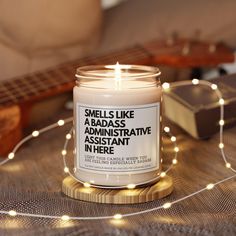 a white candle sitting on top of a wooden table next to a string of lights