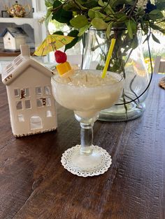 a glass filled with a drink sitting on top of a wooden table next to a house