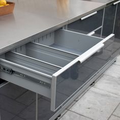 an open drawer in the middle of a kitchen counter with some lemons on it