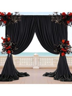 two black drapes with red flowers on them in front of a balcony overlooking the ocean