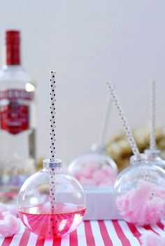 a table topped with glass balls filled with pink liquid and candy on top of it