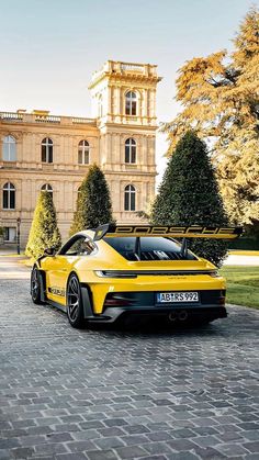 a yellow sports car parked in front of a large building