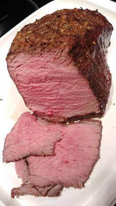 a piece of roast beef on a white plate with some seasoning sprinkled on it