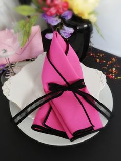 pink napkins tied together on a plate with flowers in the backgroung