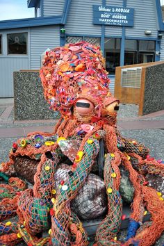 a stuffed animal made out of many different types of yarn and other things on the ground