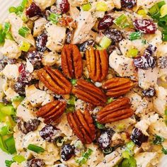 a white plate topped with chicken salad covered in pecans, cranberries and pecans