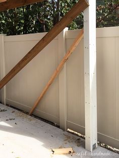 an unfinished wooden roof over a white fence