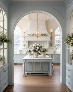 an archway leads into a kitchen with blue cabinets and white counter tops, along with flowers on the island