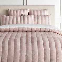 a bed with pink comforter and pillows on it