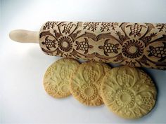 some cookies and a rolling pin on a white table with an intricate design painted on it