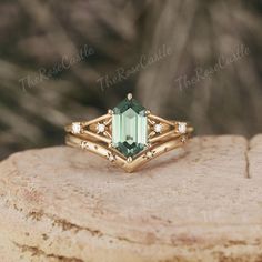 a ring with an emerald colored stone surrounded by white diamonds on top of a rock