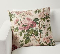 a white couch with a pink flowered pillow on it's back and side