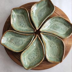 four leaf shaped dishes sitting on top of a wooden plate