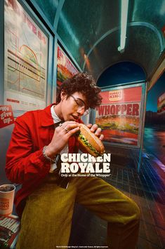 a man sitting down eating a sandwich in front of a store window with the words chicken royale on it