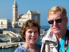 a man and woman standing next to each other in front of a body of water