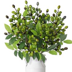 a white vase filled with green leaves and berries