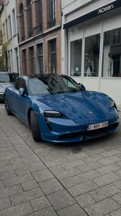 a blue sports car parked in front of a building on the side of a street