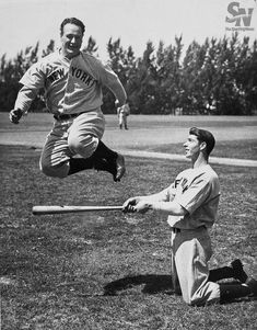 an old photo of a baseball player jumping into the air with his bat in hand