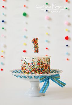 a birthday cake with sprinkles and a number one candle on the top