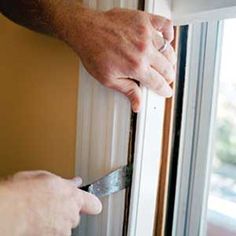 a man is holding a pair of scissors in front of a window and opening it