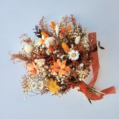 a bouquet of flowers with orange and white colors is on the table next to an orange ribbon