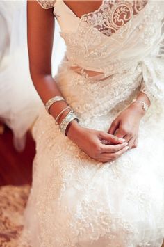 a woman in a white wedding dress sitting on a bed with her hands clasped to her chest