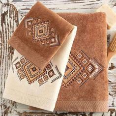 two brown and white towels sitting on top of a wooden table next to a brush