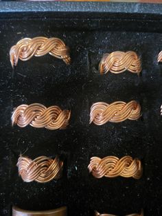 some gold colored rings are sitting in a black box on the counter next to other metal objects