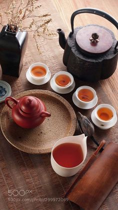 there are many cups and saucers on the table with some tea in front of them