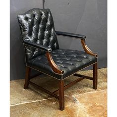 a black leather chair sitting on top of a tile floor next to a gray wall