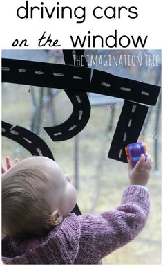 a toddler playing with a window that has cars on it and the words driving cars on the window