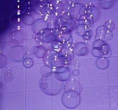 soap bubbles floating in the air on a tiled floor with purple walls and white tiles