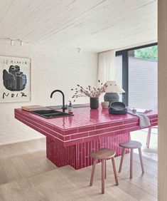 a kitchen with pink counter tops and stools