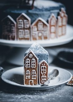 two plates with gingerbread houses on them, one is frosted and the other has powdered sugar